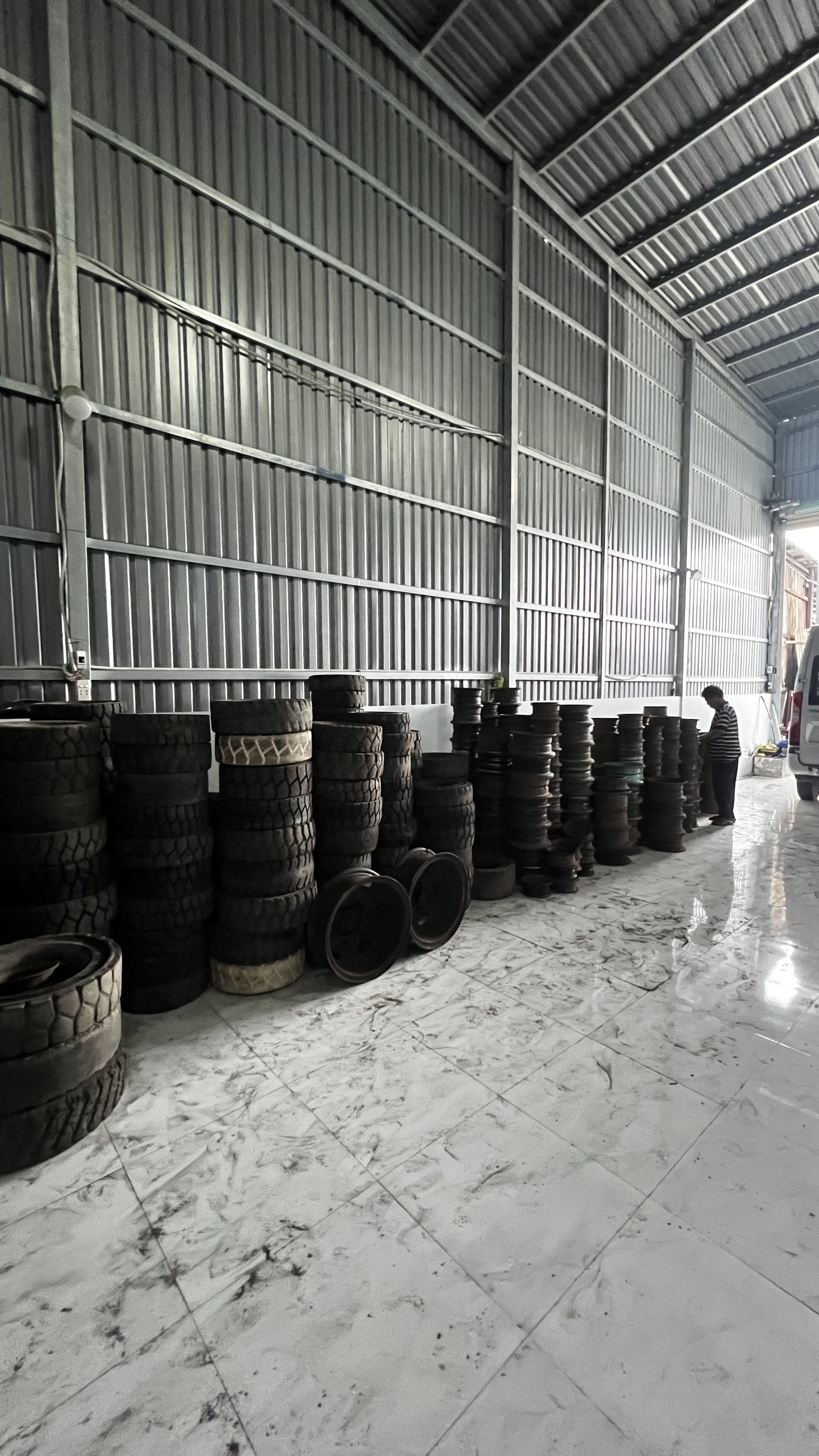 Các chồng vỏ và mâm xe nâng dọc vách kho mới trong tư liệu ngày 2 chuyển kho.